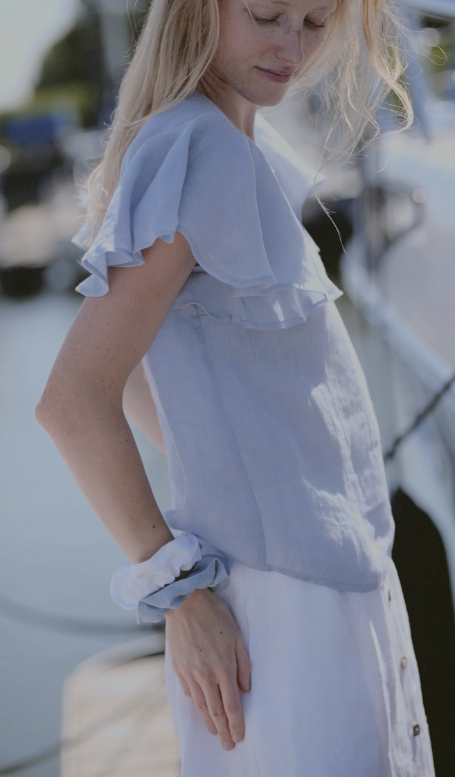 Close-up of a soft gauze linen blouse in pale blue with ruffled short sleeves